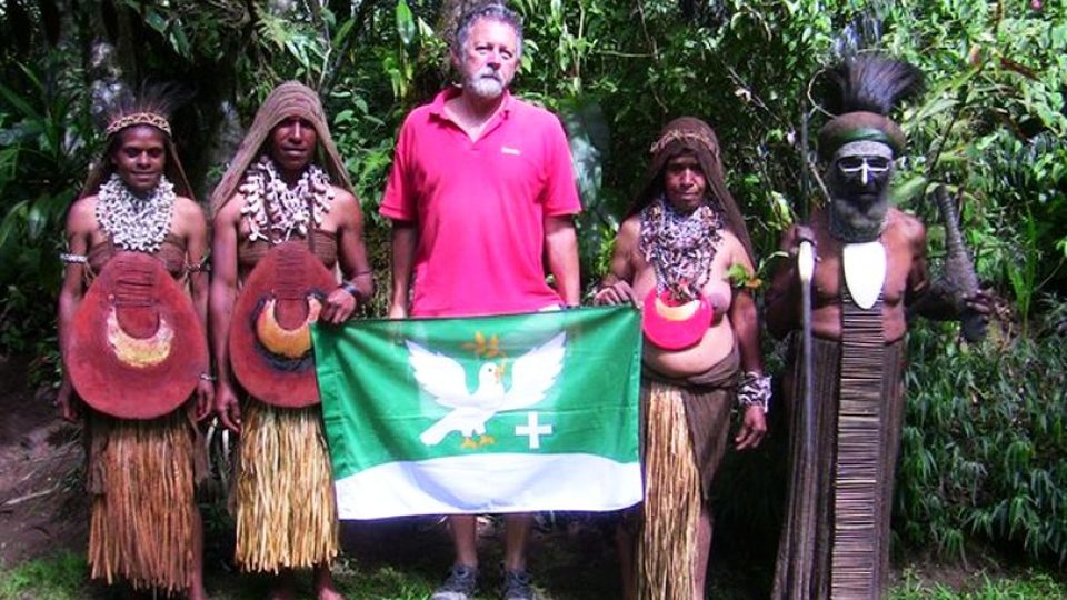 Papua - Nová Guinea - náčelník kmene PAIA s částí své rodiny (manželka a ženy jeho synů). Občan Hořiček se i s vlajkou zjevně vymyká danému prostředí