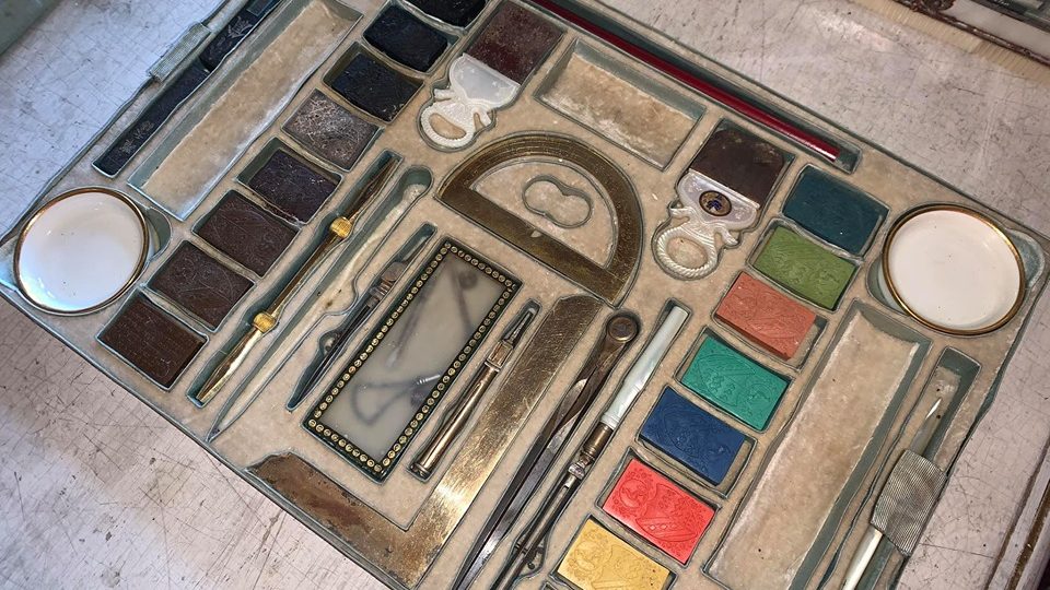 Perletí pokrytá a malbami zdobená skříňka, ve které je uloženo vše, co dáma 19. století potřebovala ke kratochvilnému konání