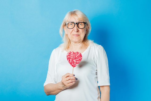 Starší žena s brýlemi drží v rukou lízátko ve tvaru srdce | foto: Profimedia